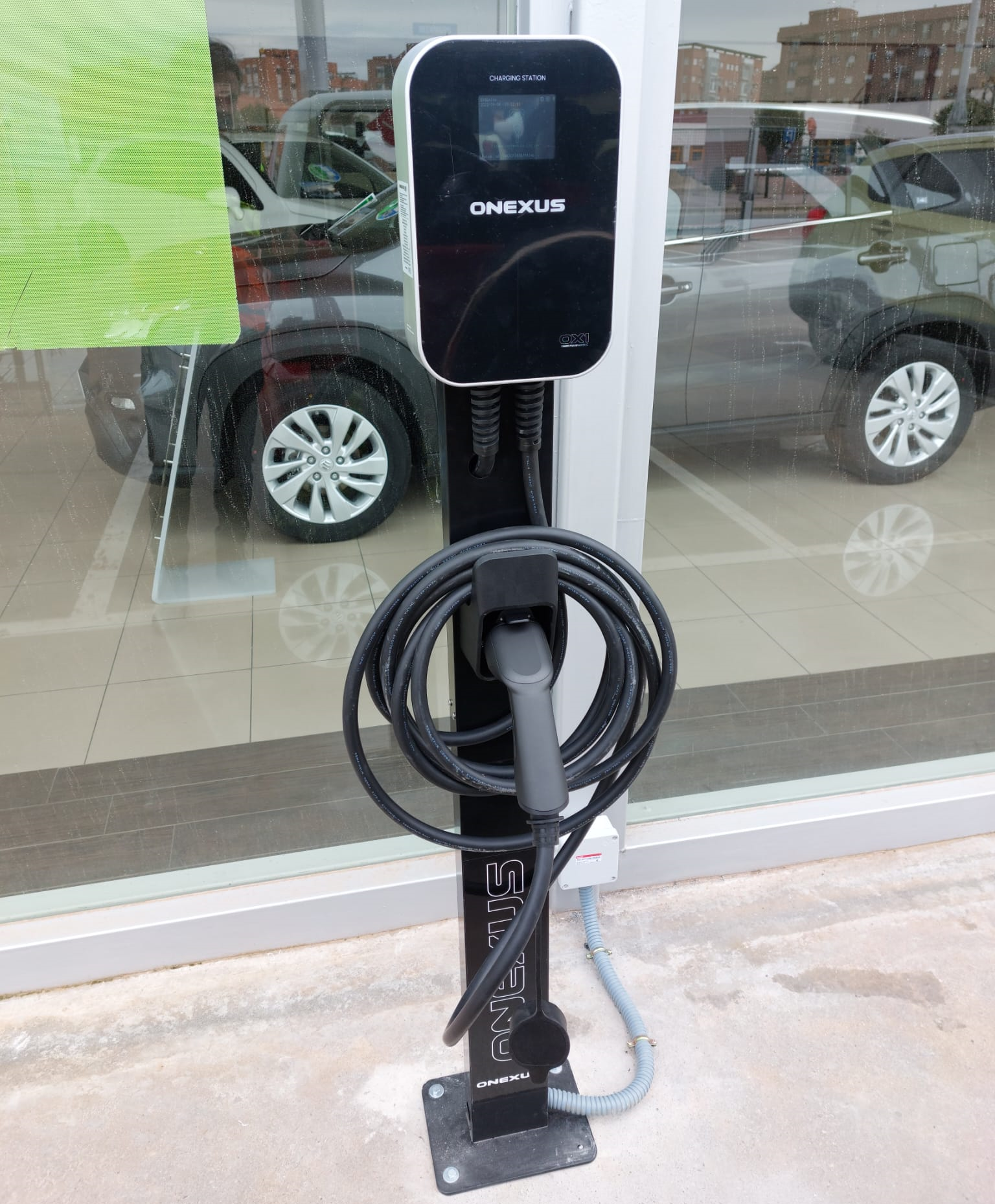 Una estación de carga para coches eléctricos está situada delante de una ventana.