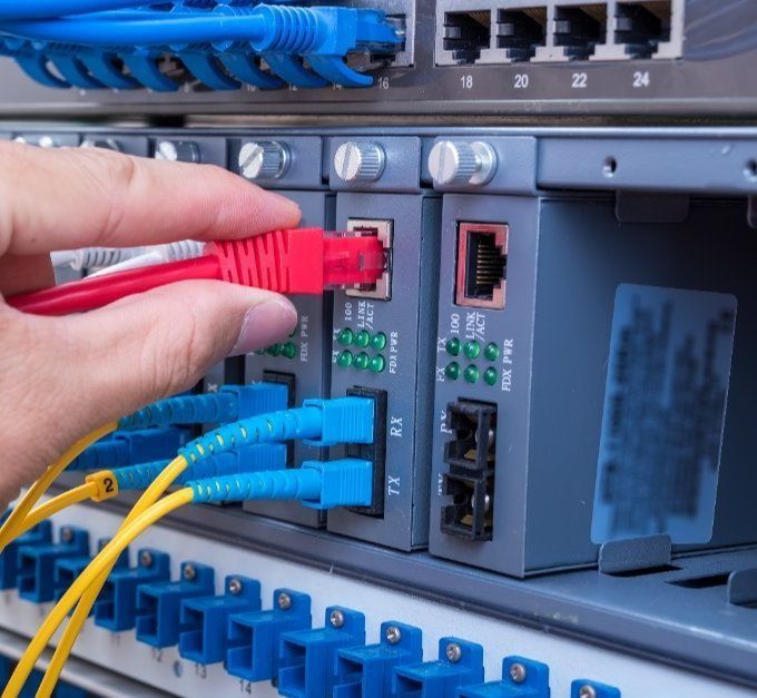 Una persona está conectando un cable rojo a un servidor.