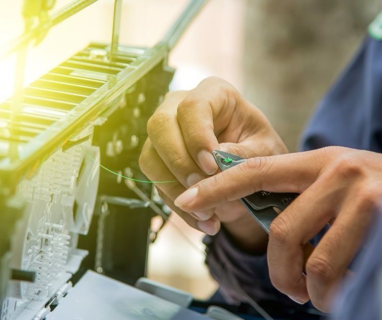 Una persona está trabajando en una máquina con un par de alicates.