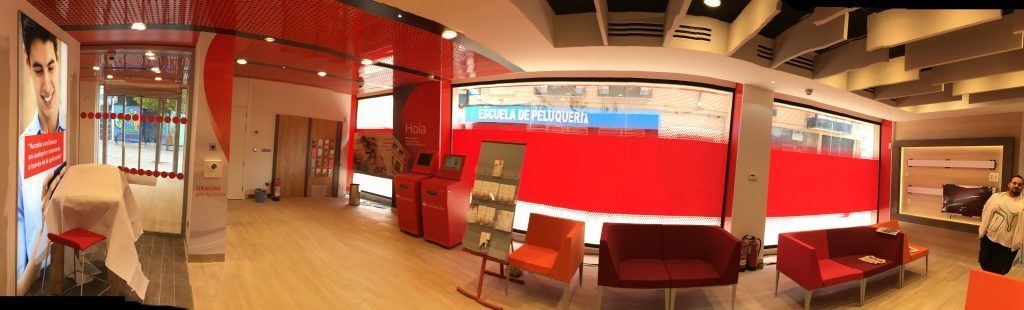 Una vista panorámica de una sala de espera con sofá rojo y sillas.